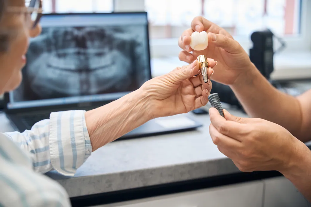 Dentist showing an implant, abutment and crown to a patient